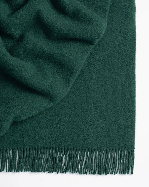 Nevis Forest lambswool throw in deep pine green, close-up showing tassel border and soft woven texture by Weave Home