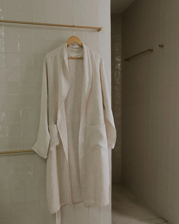 Sova Robe in Savanna, European linen wrap robe with subtle pinstripe weave and aero wash finish, hung on wooden hanger by Weave Home