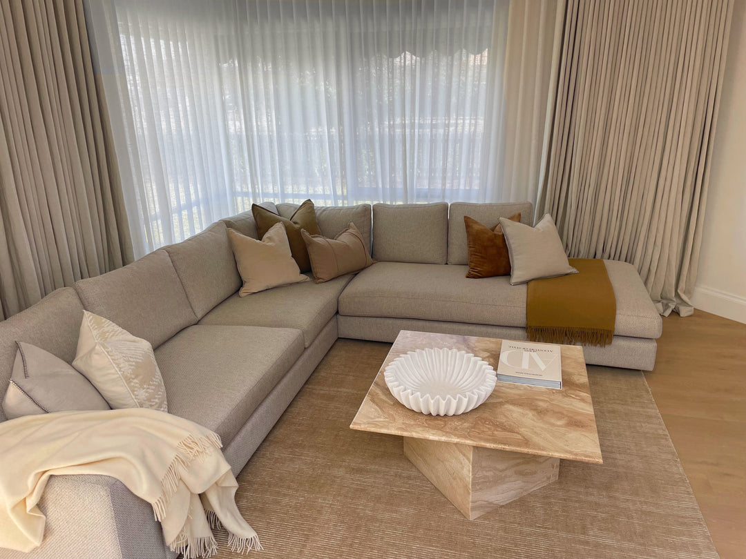 Modern living room with a sectional sofa, coffee table, and decorative pillows.