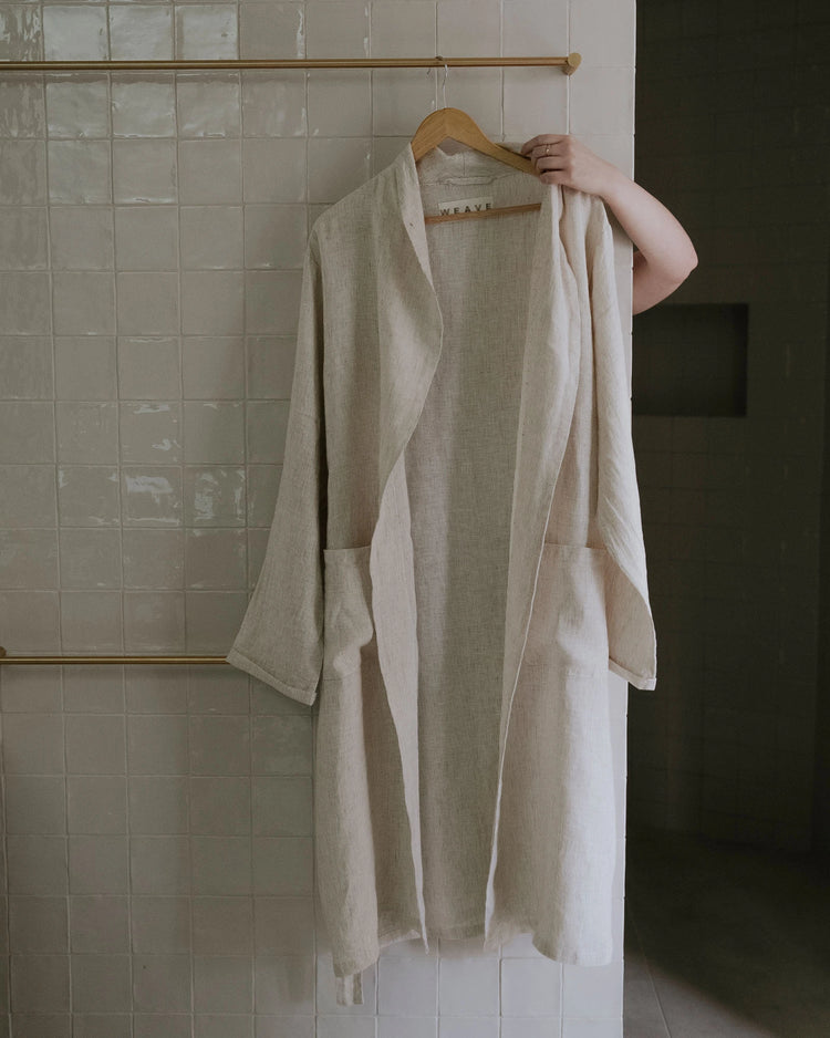 Sova Robe in Savanna, natural linen wrap robe with subtle pinstripe weave hung on wooden hanger by Weave Home