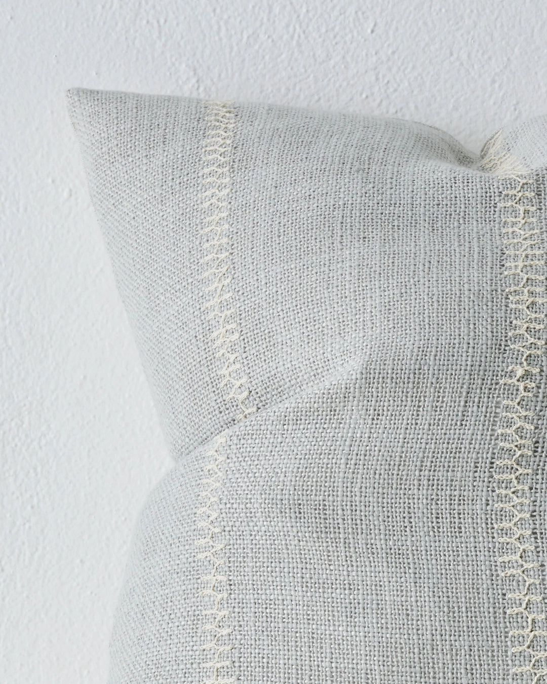 Maddalena Glacier 50x50 cushion detail, showing ice-blue polyester with delicate embroidery stitching along edge by Weave Home