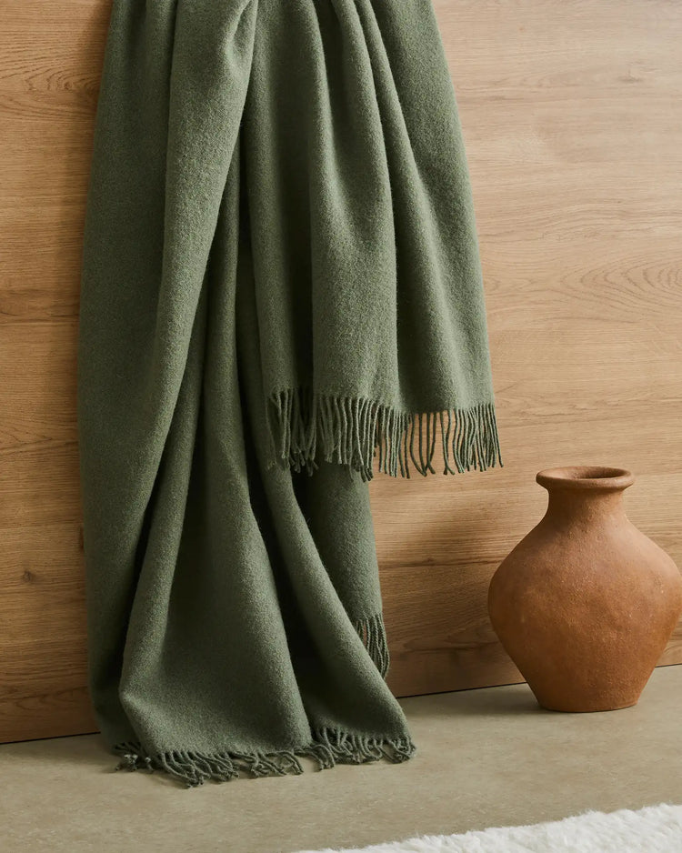 Nevis Juniper throw in soft green lambswool, draped to show texture and tassel border detail, by Weave Home