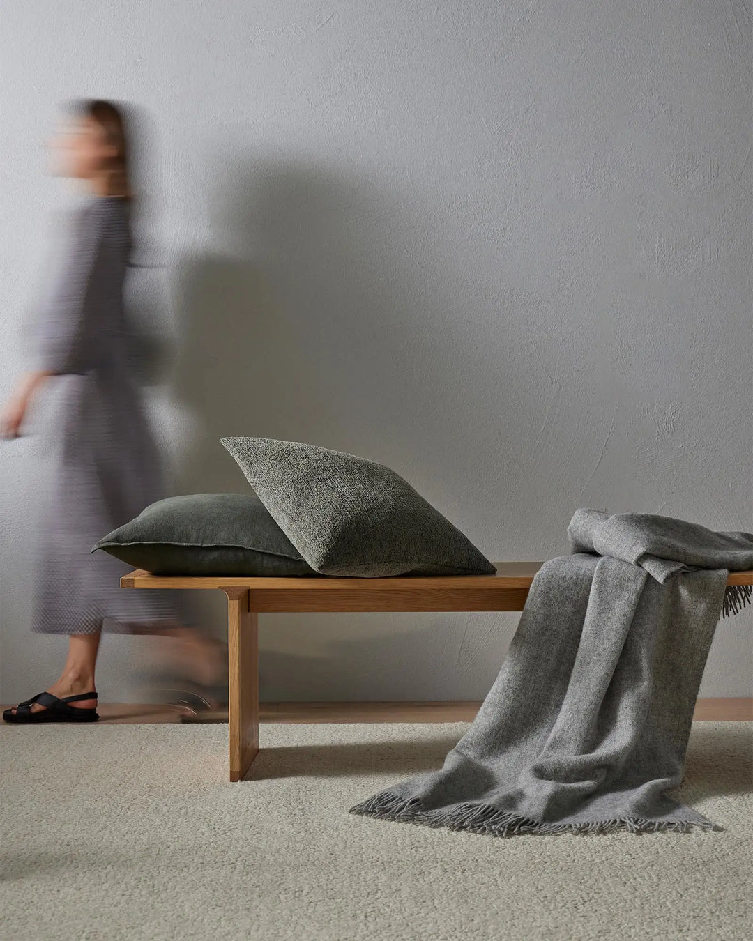 Minimalist grey interior with Marceau rug and Laurent cushions on wooden bench, textured neutral palette, soft natural light, Scandinavian aesthetic