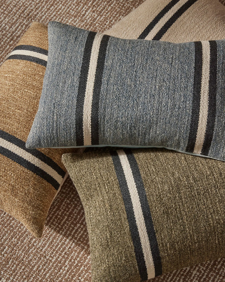 Neutral striped cushions in forest green, sage and warm sand tones layered on textured natural linen, creating an earthy, minimalist aesthetic for coastal and contemporary home styling.