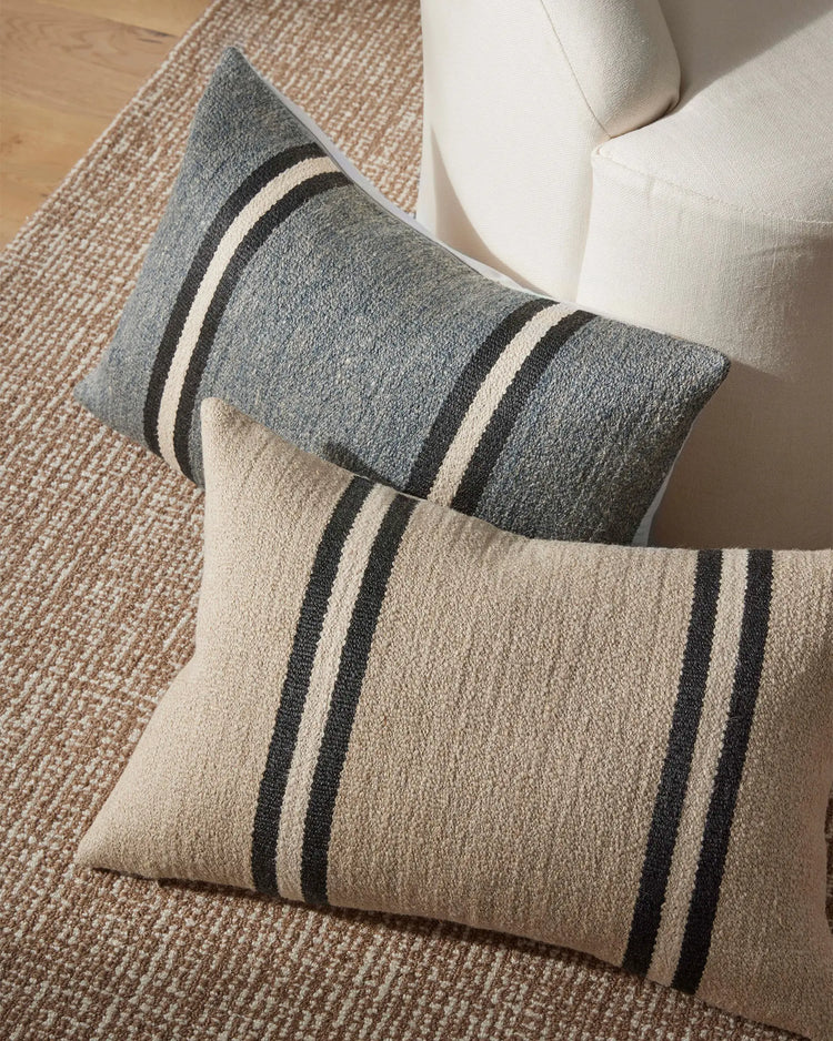 Striped wool linen cushions in charcoal and cream with black stripes, styled on neutral seating against a woven natural fibre rug