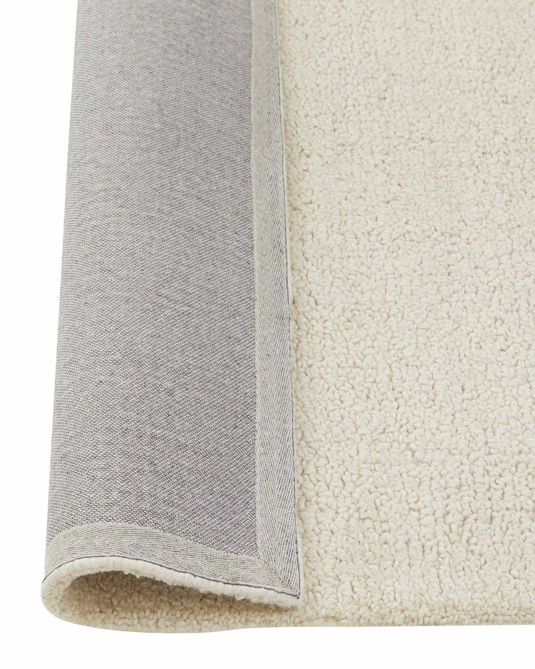 Marceau Angora wool blend rug in cream, rolled detail showing woven texture and grey binding edge by Weave Home