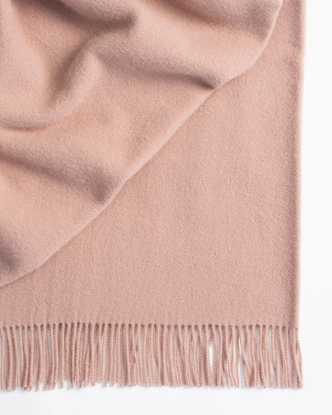 Nevis Rose lambswool throw in blush pink, close-up detail showing soft wool texture and tassel fringe border by Weave Home