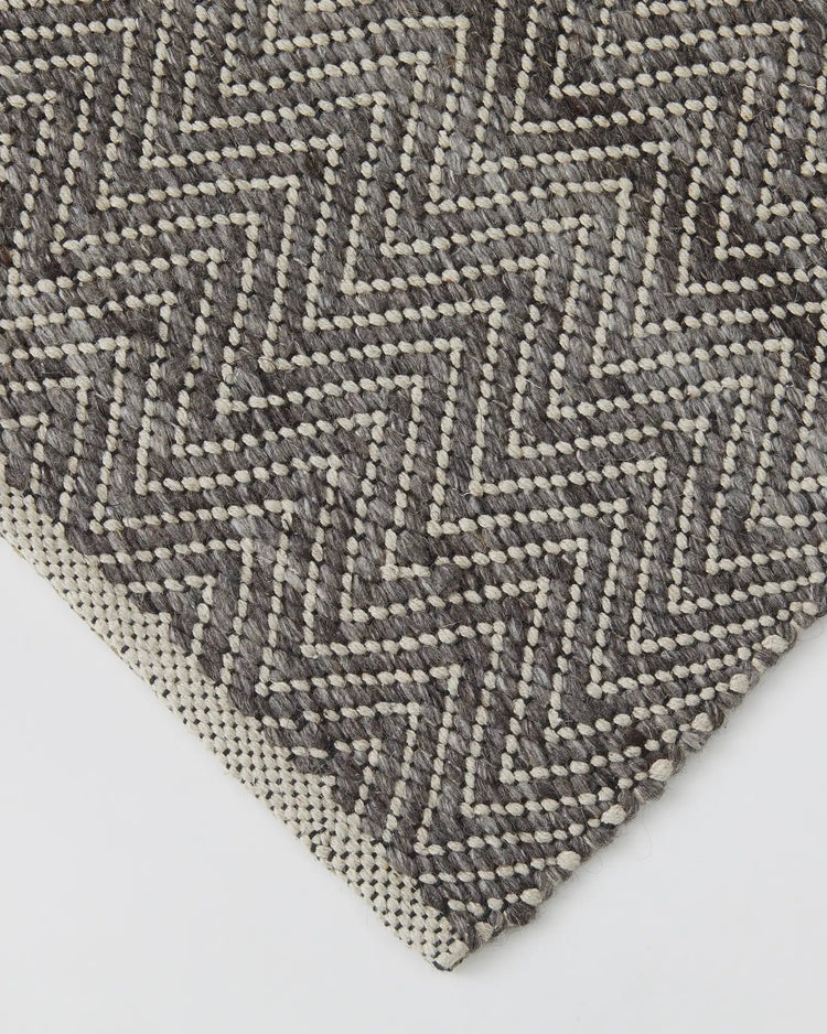 Matterhorn Tar rug detail, charcoal grey and ivory wool-cotton chevron weave with cotton braided edge by Weave Home