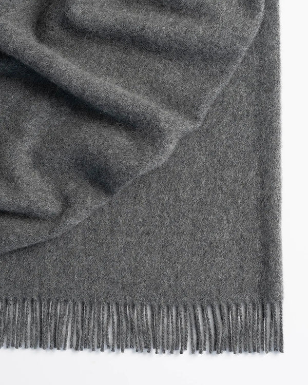 Nevis Charcoal throw in mid-toned grey lambswool with tassel fringe border, textured weave detail by Weave Home