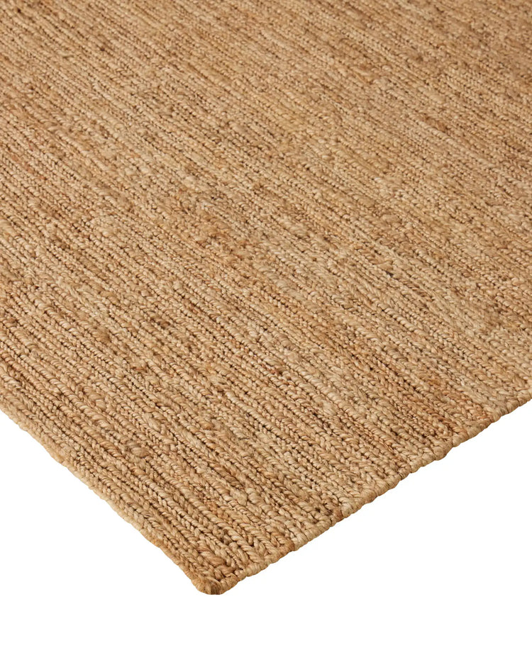 Suffolk Natural jute rug corner detail, hand-woven textured weave in golden brown with cotton edging by Weave Home