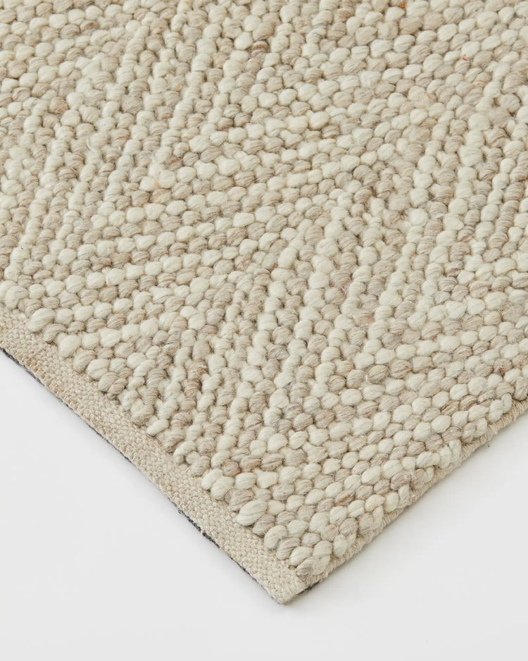Zambesi Sandstorm rug detail, showing tightly woven chevron pattern in natural wool blend with cotton braided edge by Weave Home