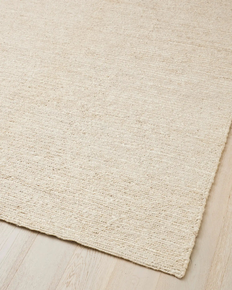 Suffolk Pearl textured jute rug in warm ivory, hand-woven plain weave with cotton backing visible at corner, by Weave Home
