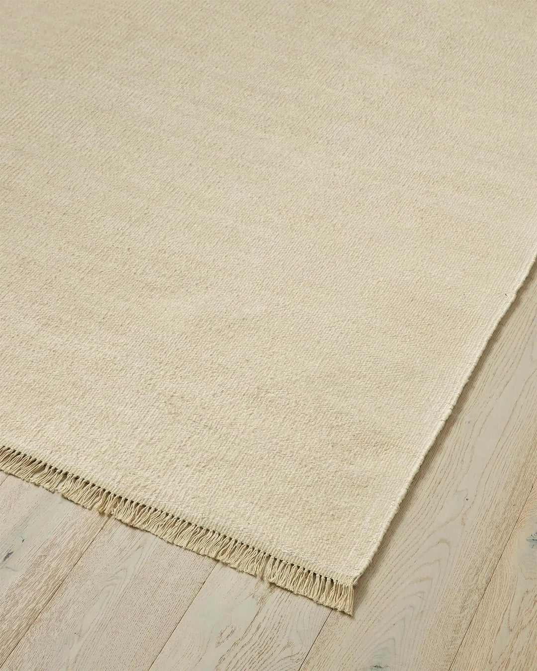 Emilio Canvas linen rug in light beige, corner detail showing fringe edge and flat-weave texture by Weave Home