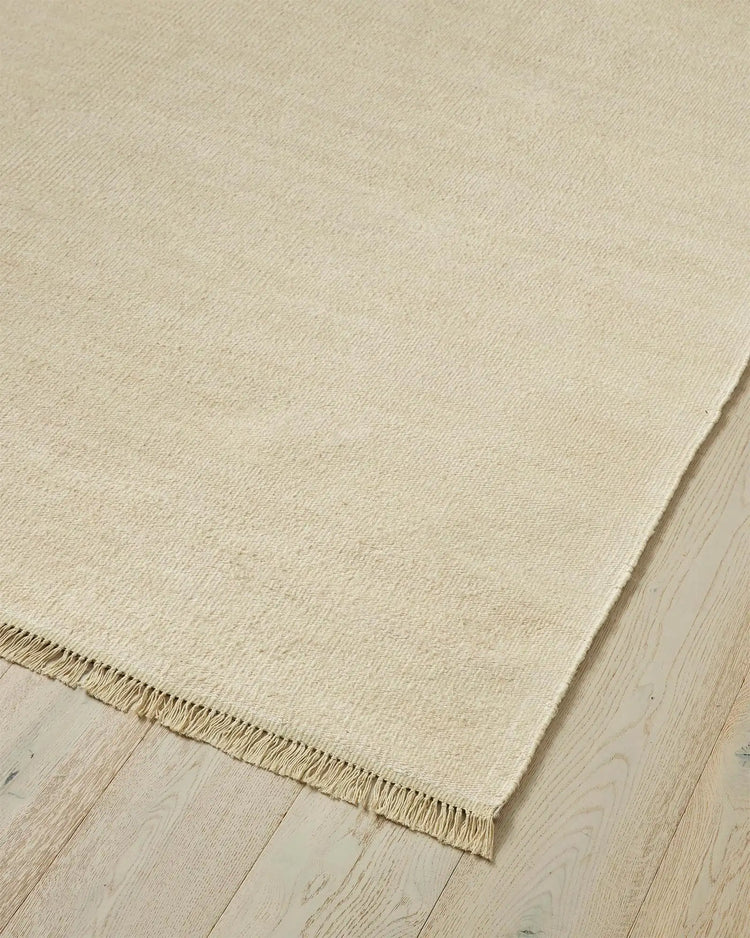 Emilio Canvas linen rug in light beige, corner detail showing fringe edge and flat-weave texture by Weave Home