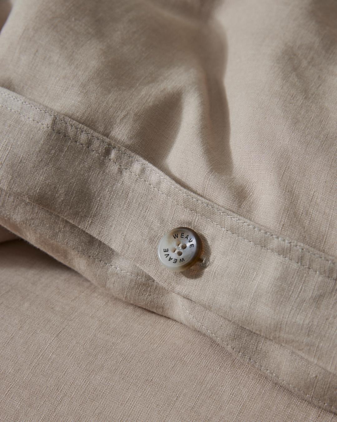 Ravello Quilt Cover Shell, close-up detail of branded button closure and internal tie on natural linen by Weave Home