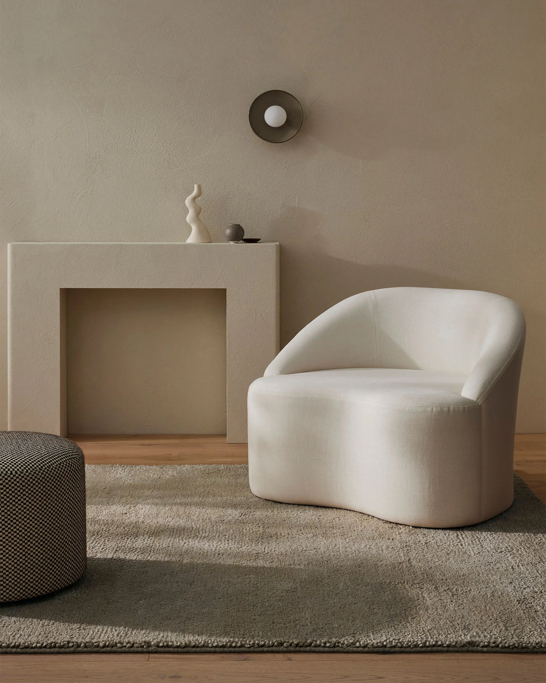 Minimalist living room with cream upholstered chair, neutral textiles, and Valencia Cloud wool rug in soft greige tones layered across warm timber flooring