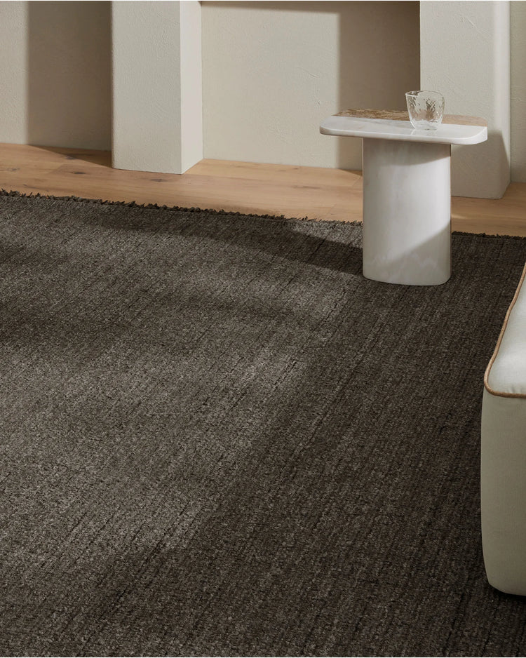 Minimalist room with charcoal textured wool-blend rug anchoring warm timber flooring, paired with cream architectural elements and white side table for serene Scandinavian-inspired interiors