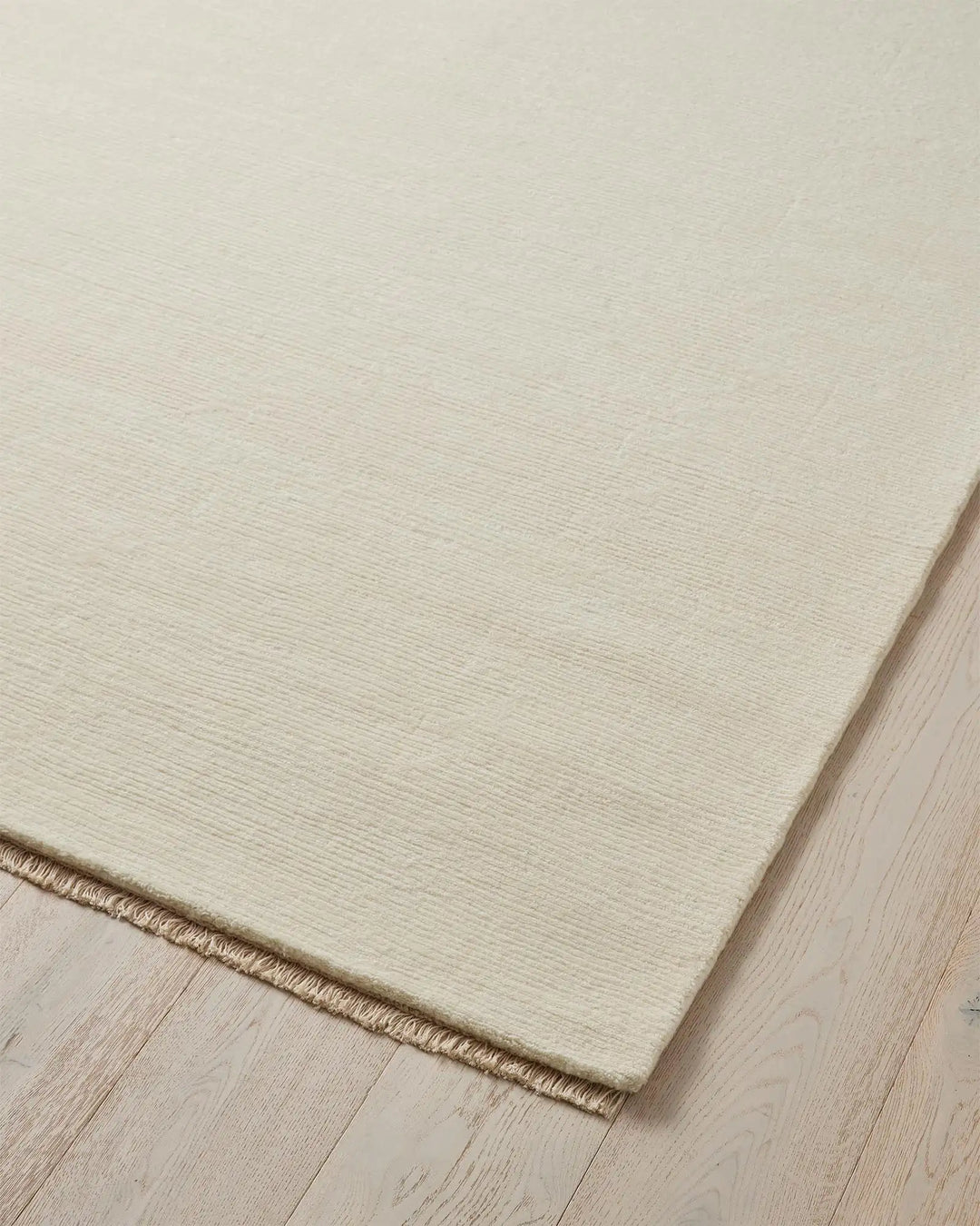 Alessandre Seasalt rug corner detail, hand-woven NZ wool in cool ivory with blanket stitch edge by Weave Home