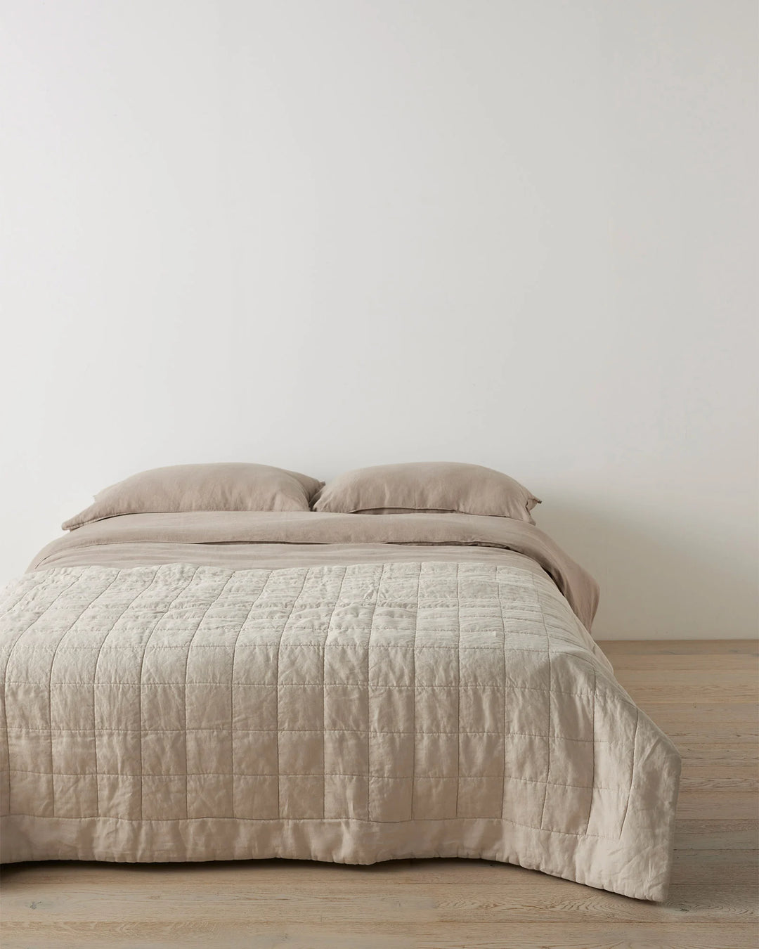 Neutral bedroom with Ravello Coverlet in bone linen, featuring quilted grid pattern and soft taupe tones over minimalist bed styling