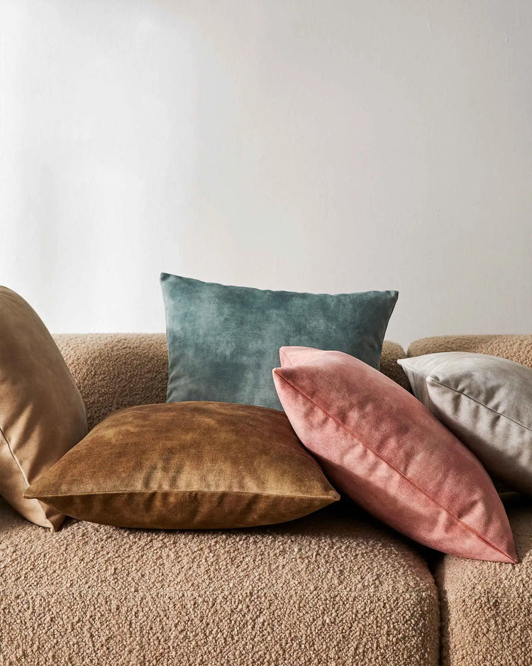 Neutral linen sofa styled with Ava cushions in muted teal, dusty rose and caramel velvet tones, creating a soft, contemporary colour palette against cream walls