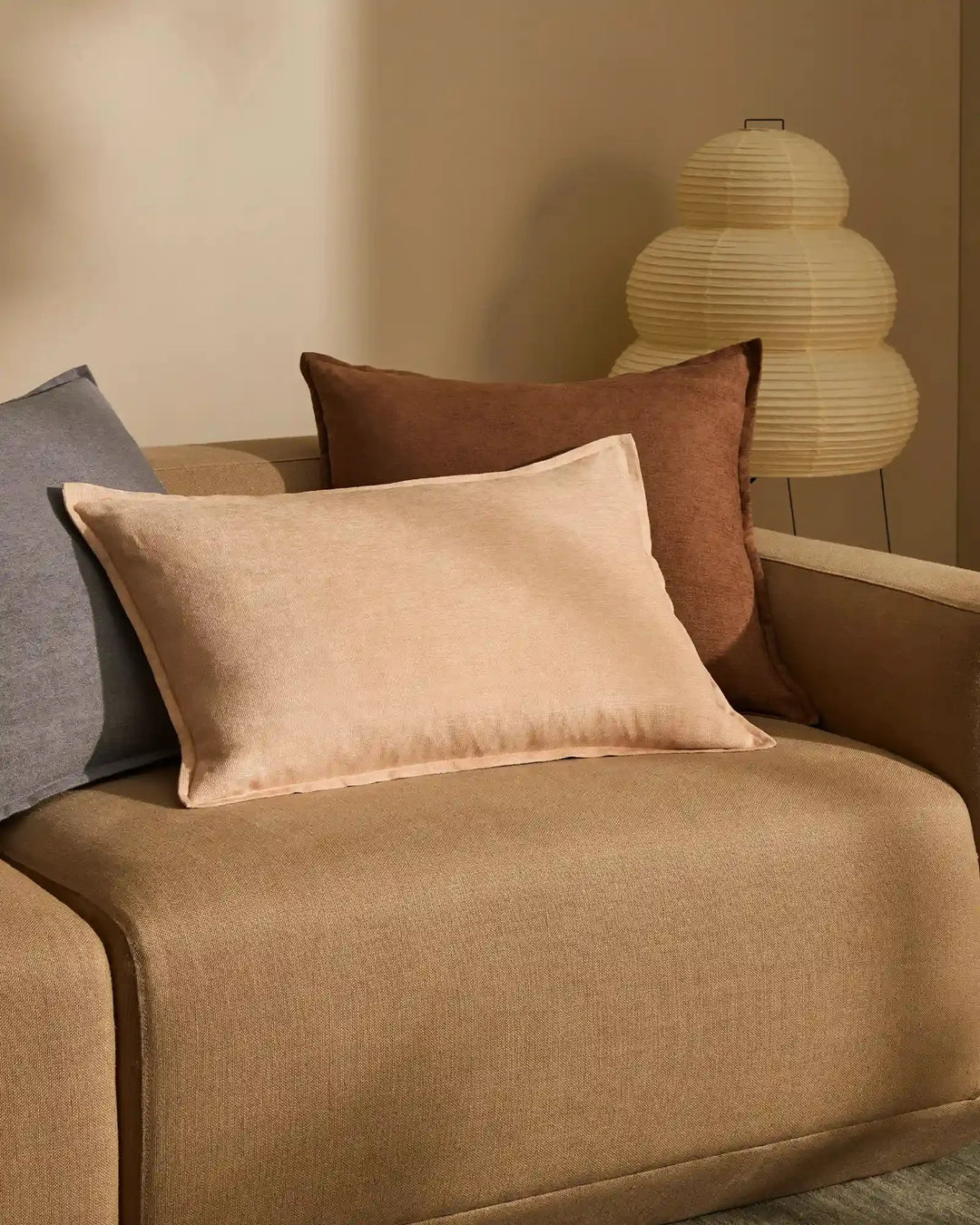 Warm earth-tone living room styled with Fiore cushions in nectar and denim on a camel upholstered sofa, layered with soft textures and neutral palette lighting