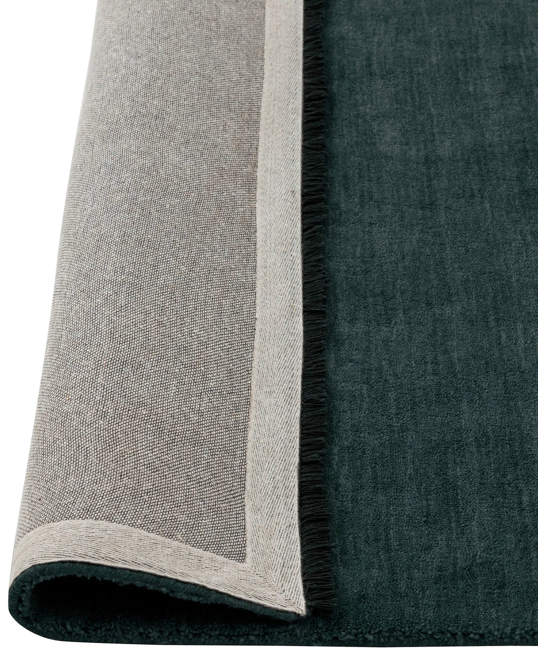 Silvio Dusk high traffic rug, deep muted blue with cream micro fringe border detail, rolled to show sustainable weave construction by Weave Home