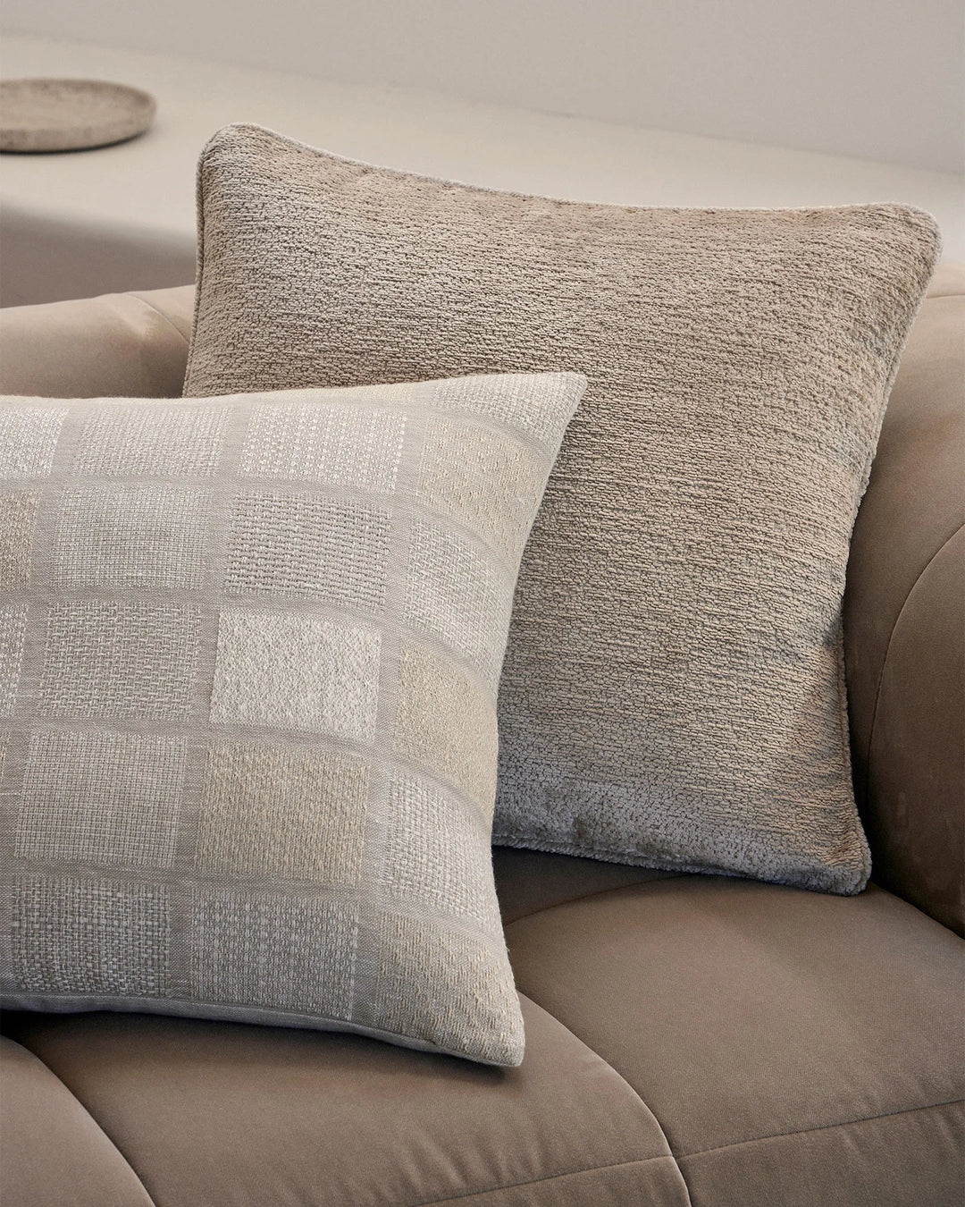 Neutral cushion styling on taupe sofa featuring textured linen-cotton and jacquard weave designs in cream and greige tones
