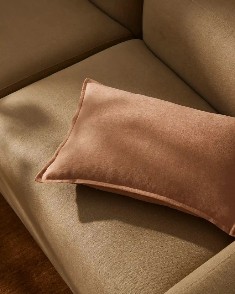 Terracotta linen cushion nestled on a warm neutral armchair, layered earth tones and soft textures creating a minimalist, relaxed aesthetic