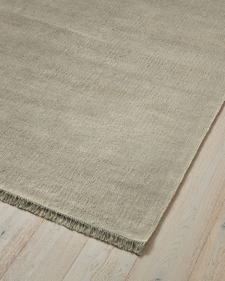 Emilio Oyster linen rug in pale grey, close-up showing flat-weave texture and fringed edge detail by Weave Home