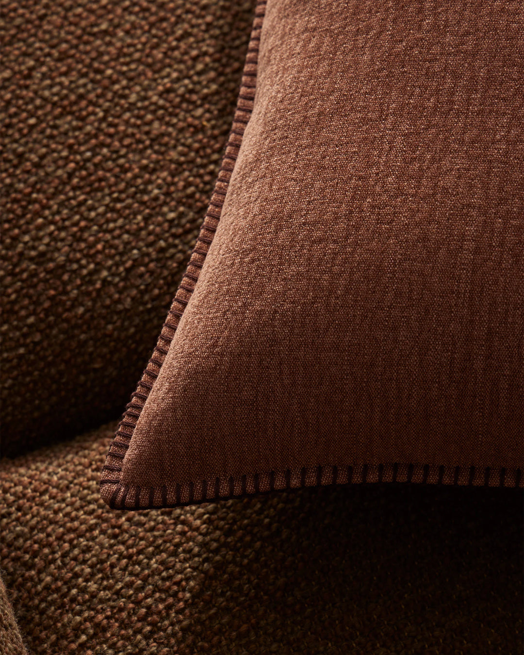 Close-up of terracotta linen texture with blanket stitch detail, layered fabric showing warm earthy tones and natural woven surface