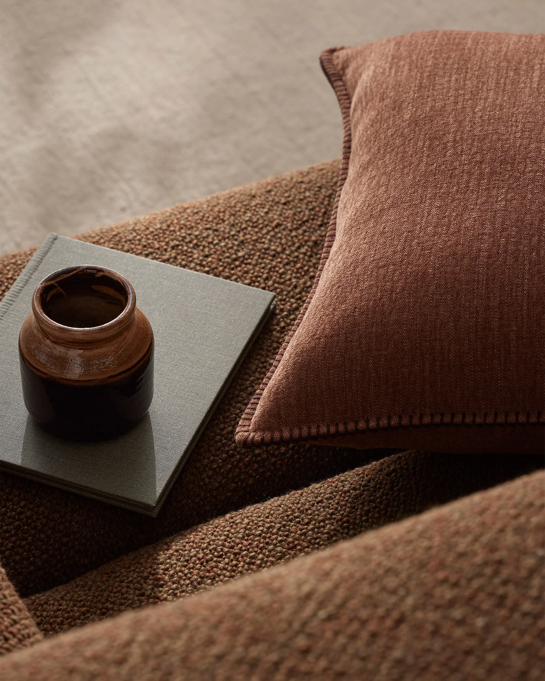 Earthy terracotta and neutral tones layer in a serene interior scene with Alba linen cushion, textured weave, and minimalist styling