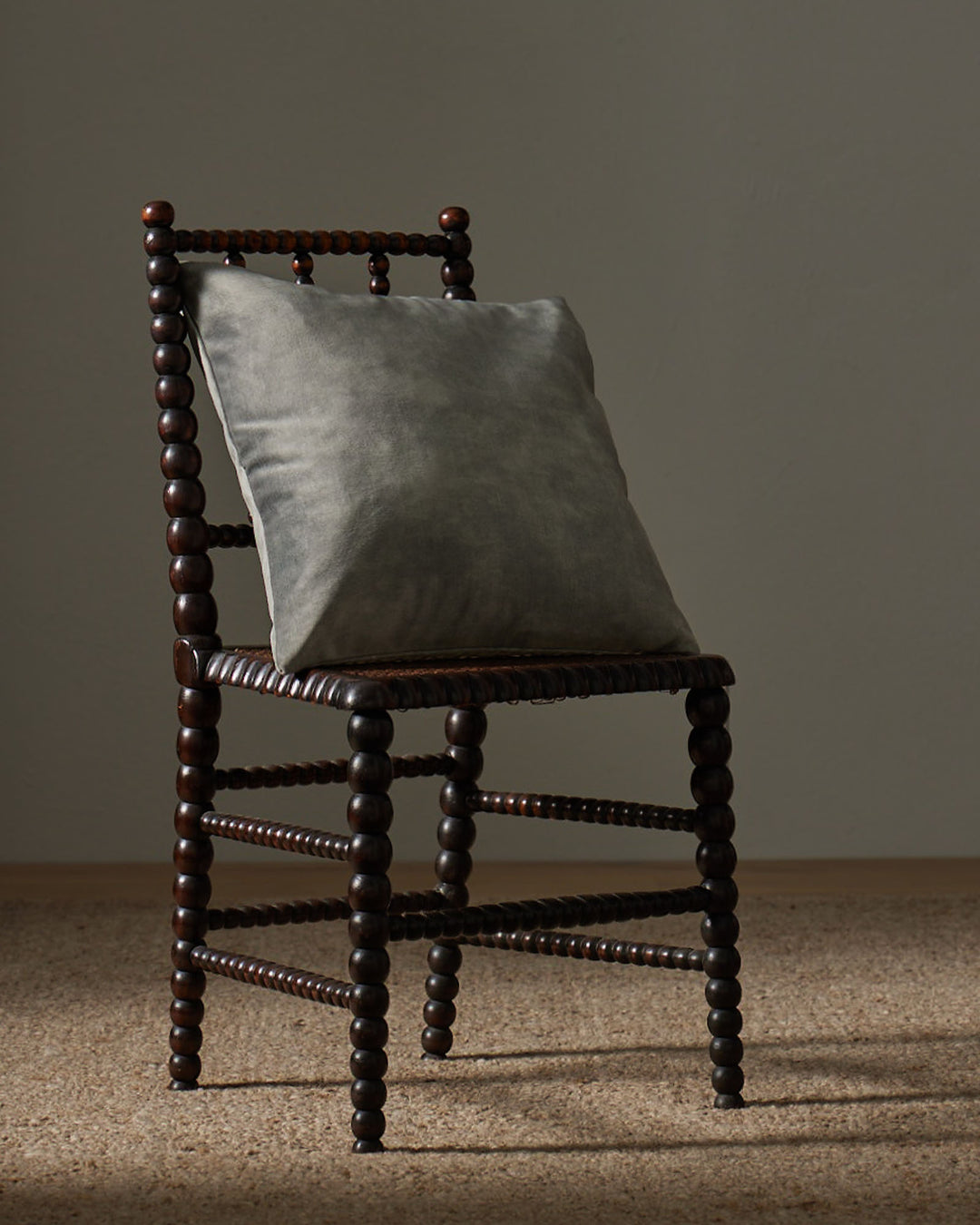 Ava Steel 50x50cm cushion in smoky grey polyester with velvet-like texture, styled on wooden chair by Weave Home