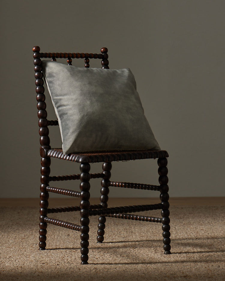 Ava Steel 50x50cm cushion in smoky grey polyester with velvet-like texture, styled on wooden chair by Weave Home