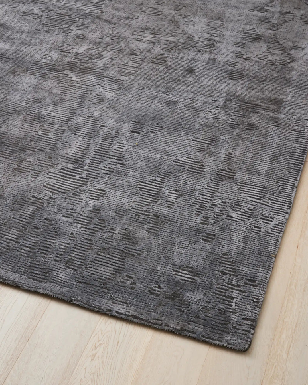 Glebe Shadow hand-woven viscose blend rug in charcoal grey, showing textured weave detail and full cotton backing on light wood floor by Weave Home