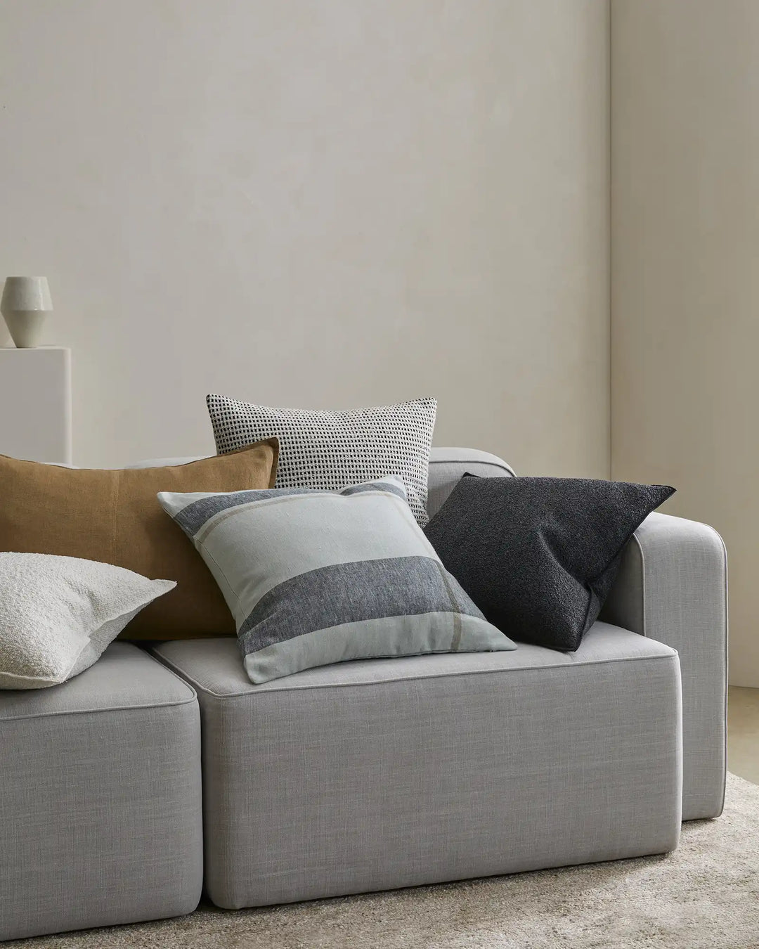 Dante Laurel linen cushion in cream and grey placement check, 50x50cm, styled with coordinating cushions on light grey sofa by Weave Home