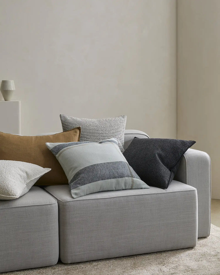 Dante Laurel linen cushion in cream and grey placement check, 50x50cm, styled with coordinating cushions on light grey sofa by Weave Home