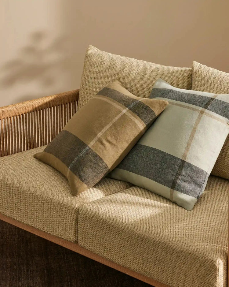 Neutral linen cushions with earthy striped patterns styled on a beige upholstered sofa with wooden slat back, creating a warm, minimalist aesthetic with layered natural textures
