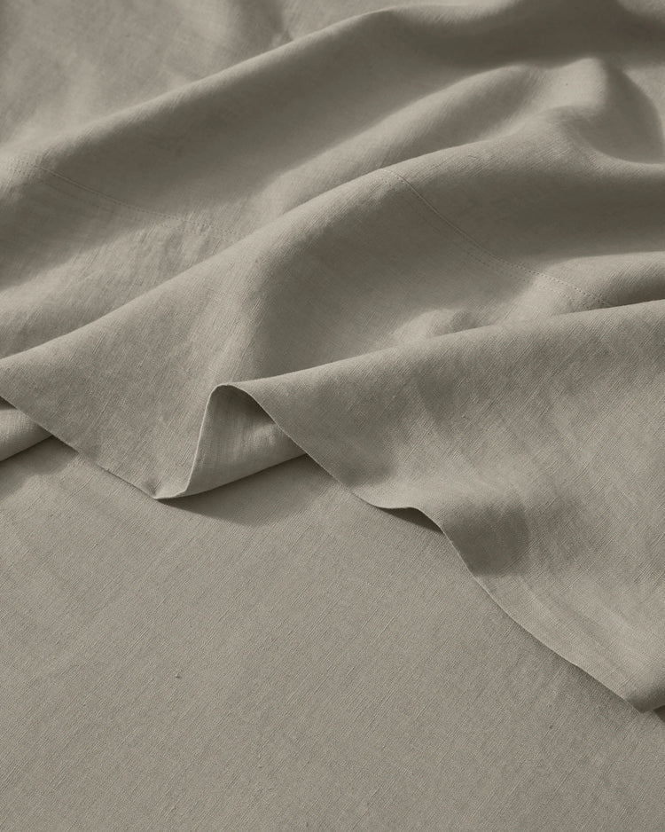 Close-up of soft pebble linen bedding with natural texture and folds, showing lightweight European linen weave in neutral warm tones