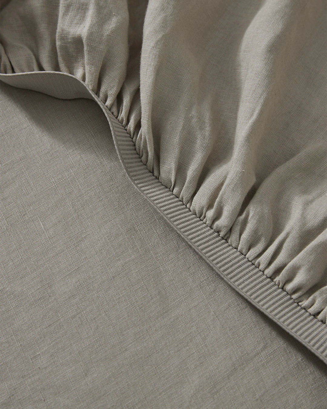 Ravello Fitted Sheet in Pebble, detail view of elastic-gathered corner with thick binding seam, European linen by Weave Home