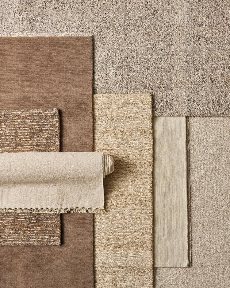 Neutral textile palette featuring layered rugs in linen, jute and wool blend with varied weave textures, from soft cream to warm taupe tones