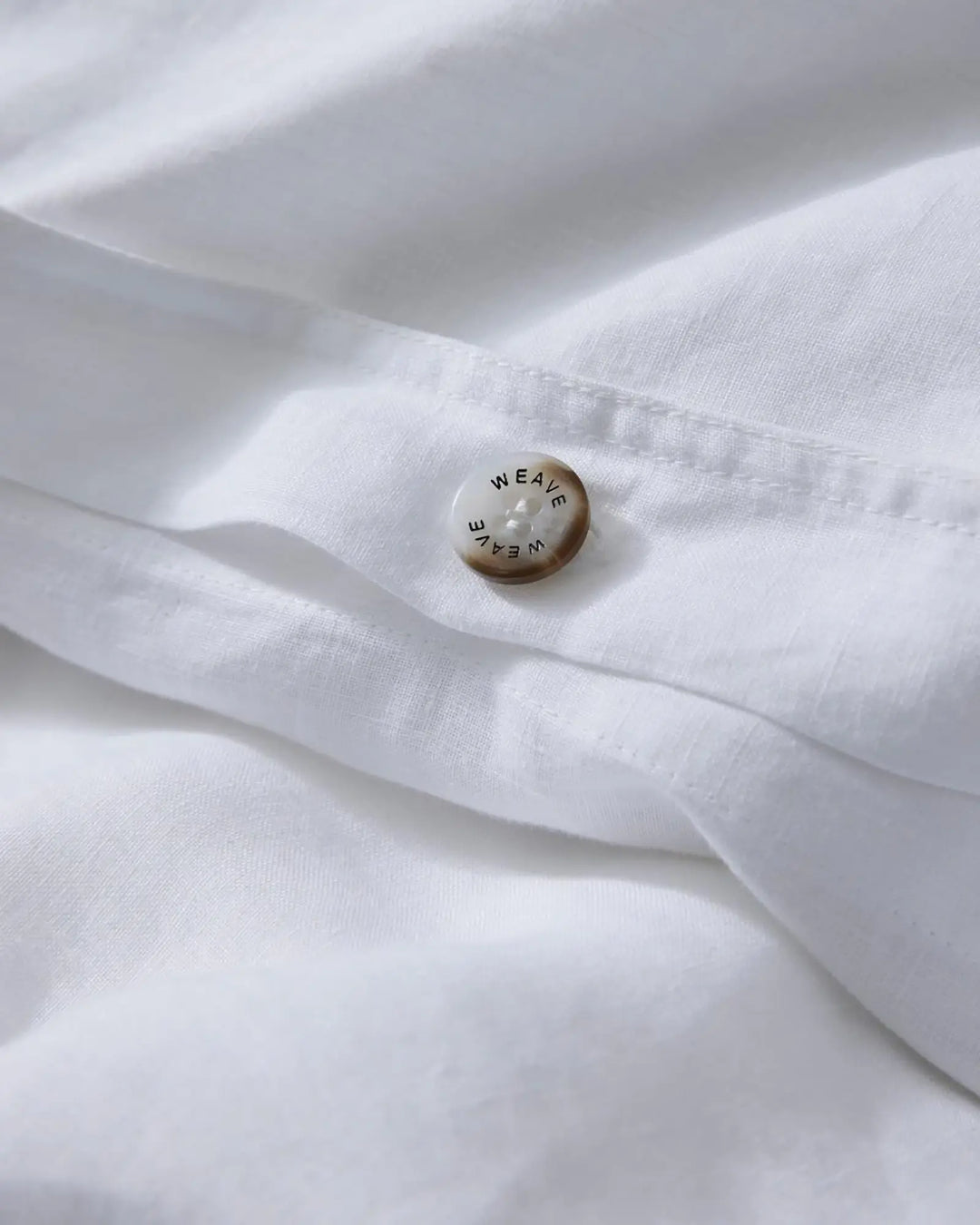 Ravello Quilt Cover in white European linen, detail shot of branded button closure by Weave Home