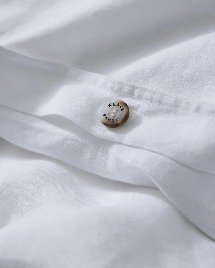 Ravello Quilt Cover in white European linen, detail shot of branded button closure by Weave Home