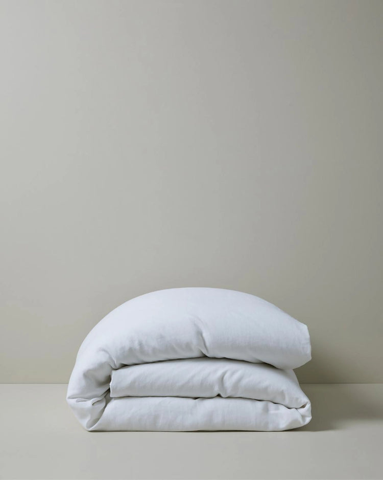 Ravello Quilt Cover in white European linen, folded and stacked on grey background, by Weave Home