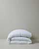 Ravello Quilt Cover in white European linen, folded and stacked on grey background, by Weave Home