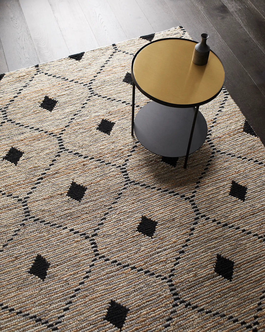 Natural jute rug with geometric black diamond pattern styled with mustard and charcoal side table on light wood floor