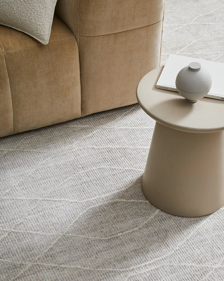 Neutral living room with Katari Moon rug in soft cream and beige tones, viscose weave creating textured diamond pattern anchoring a camel linen sofa and minimalist decor