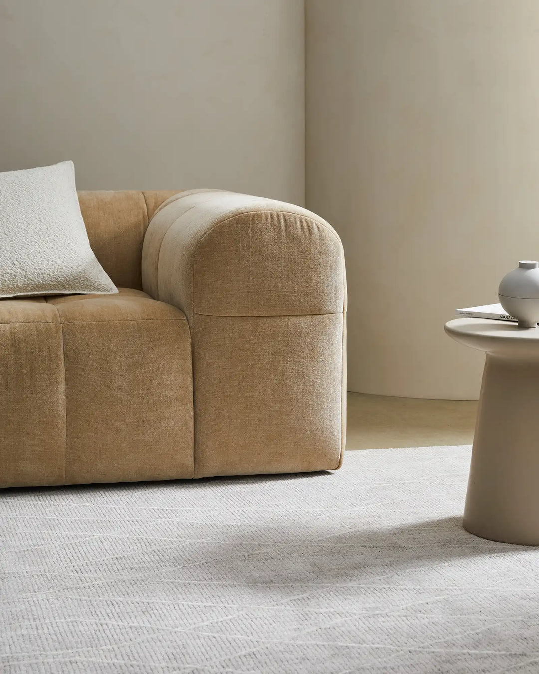 Neutral living room with cream and taupe toned Katari rug, textured white pillow on camel linen sofa, soft earth-toned interior styling with minimal aesthetic and natural light