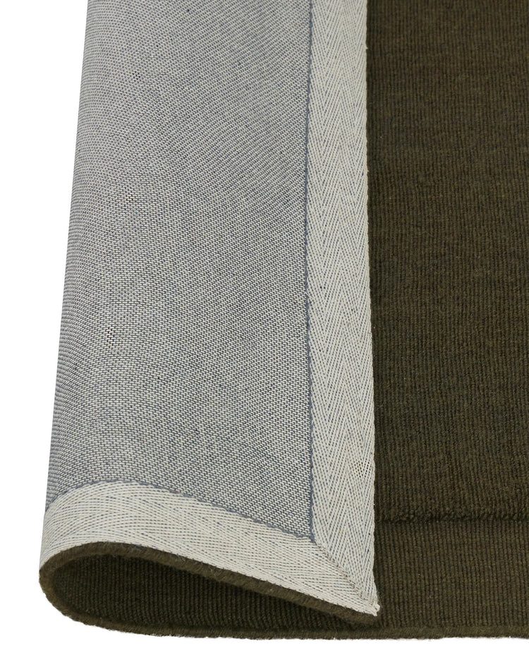 Cassio Jasper rug in deep olive with serged edge detail, 100% NZ wool loop pile construction by Weave Home