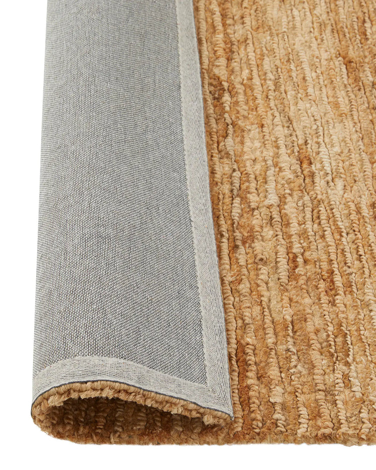 Bastian Natural jute rug detail showing looped and cut pile texture in golden-brown, with woven edge binding, by Weave Home