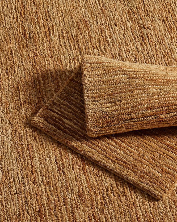 Jute rug layered with textured throw in warm natural tones, showcasing woven texture detail and earthy neutral palette